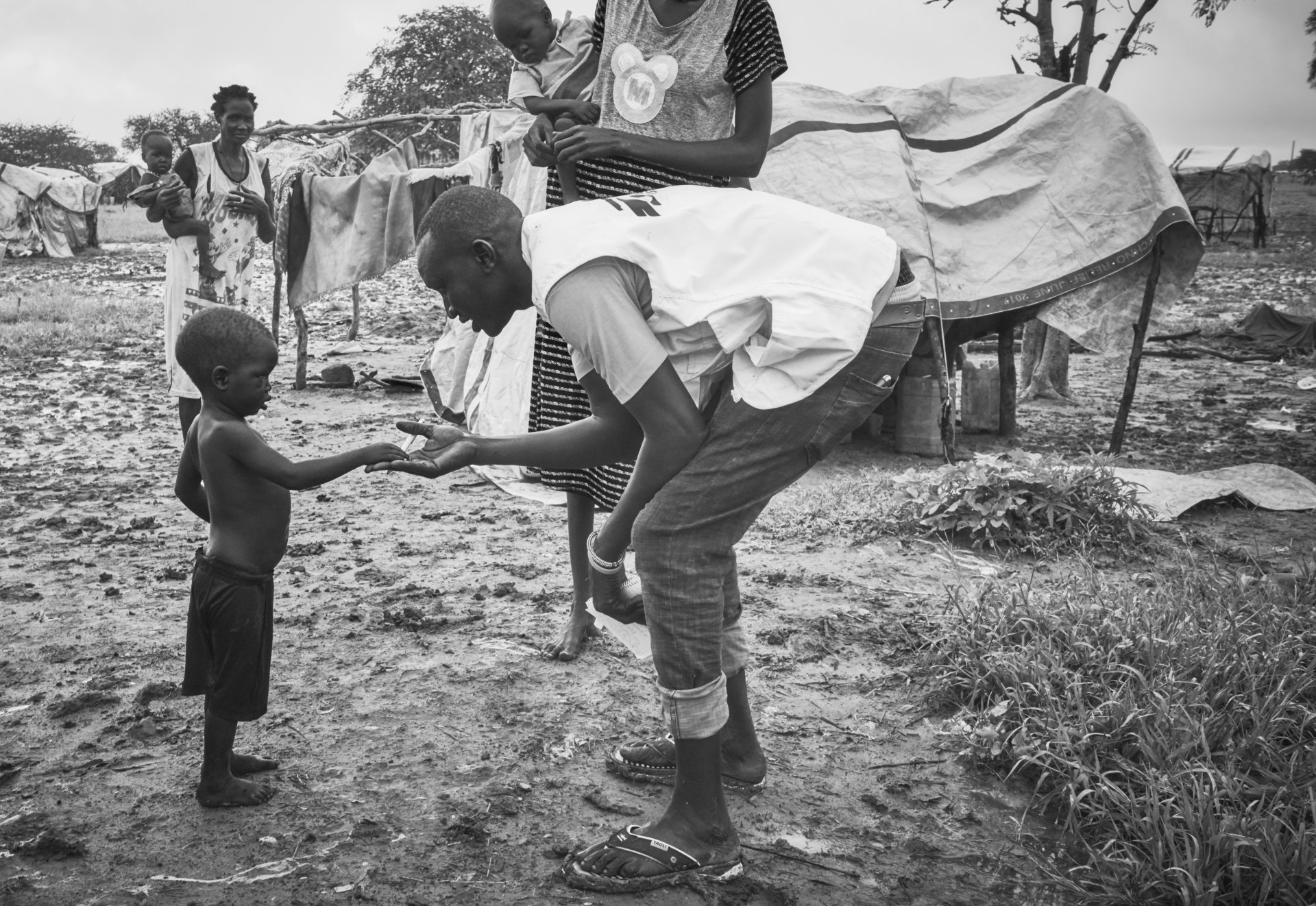 MSF staff greets one of the children of the IDP camp in Abyei. Their makeshift shelters are flooded daily.