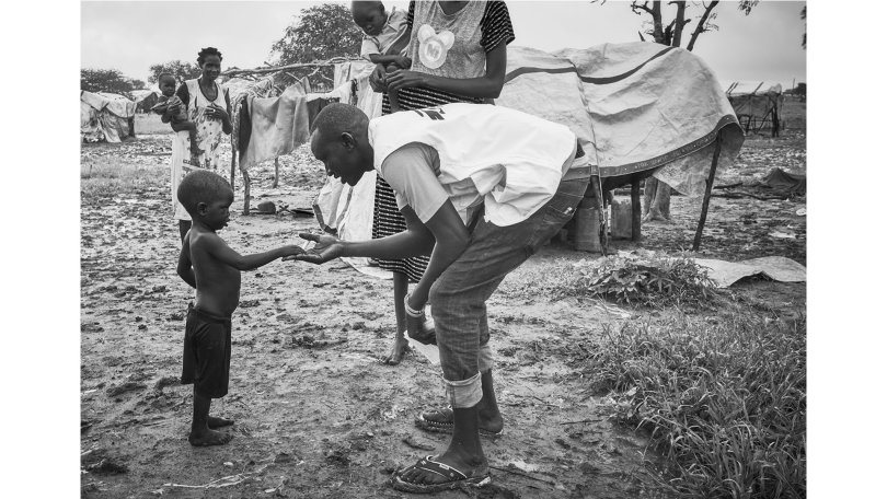 MSF staff greets one of the children of the IDP camp in Abyei. Their makeshift shelters are flooded daily.