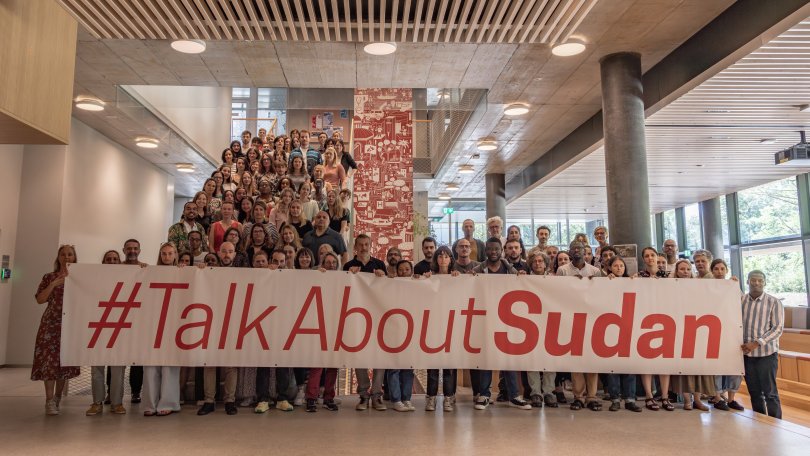 Mitarbeiter des Hauptsitzes von MSF Schweiz halten ein Banner mit der Aufschrift "#TalkAboutSudan" zur Unterstützung der sudanesischen Bevölkerung.